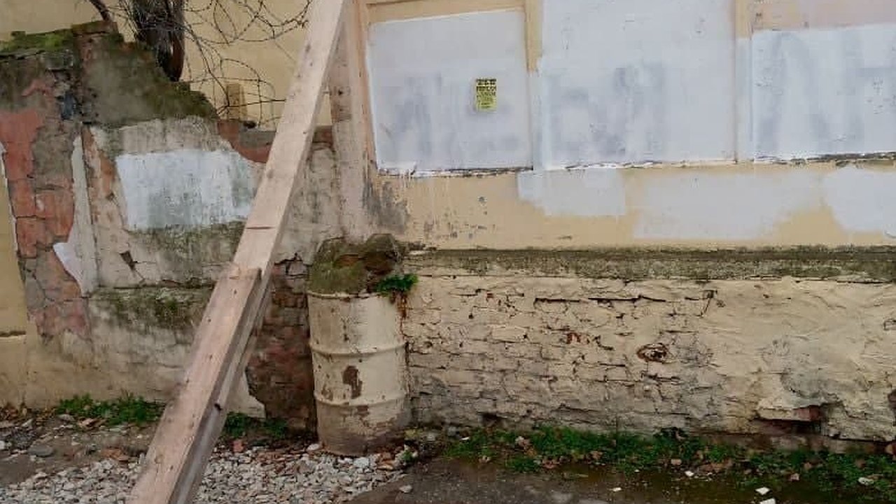 Главная картинка новости: В центре Новороссийска рушащийся бетонный забор подперли доской